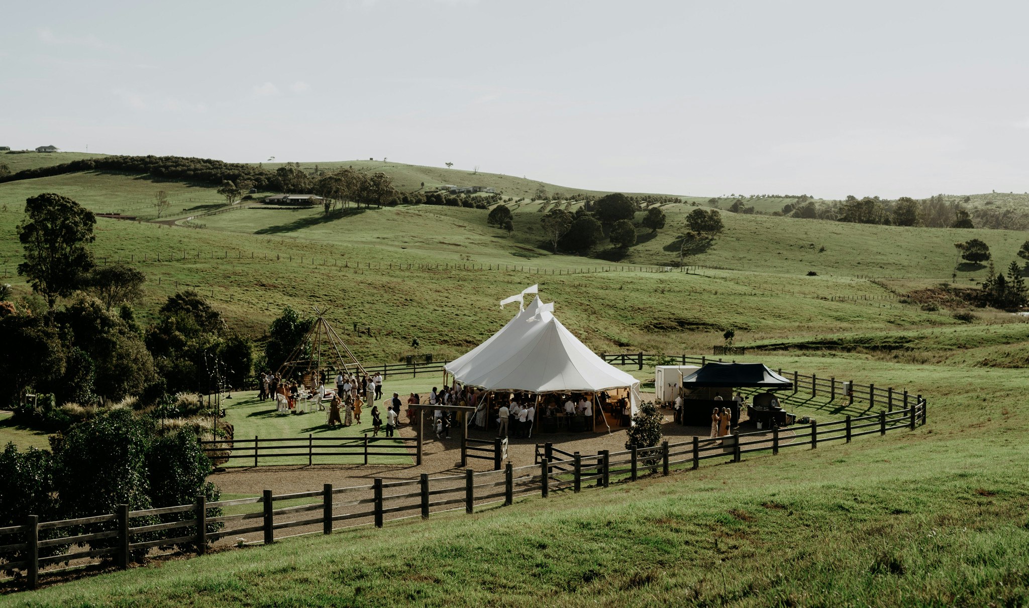 Rolling green hills surround a tipi wedding reception.